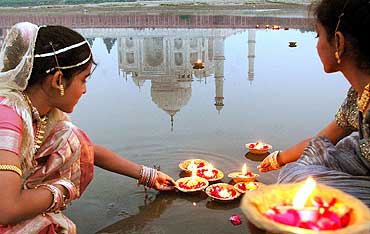 Teenagers place oil lamps on the Yamuna river behind the Taj Mahal