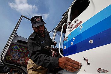 A policeman inspects a bullet riddled truck, which was carrying supplies to Kabul, after it was attacked while leaving Karachi for Kandahar