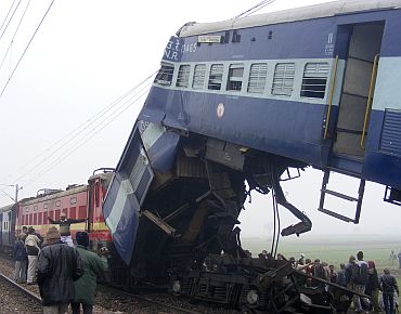 Onlookers gather around the wreckage of a train at the site of an accident in Etawah