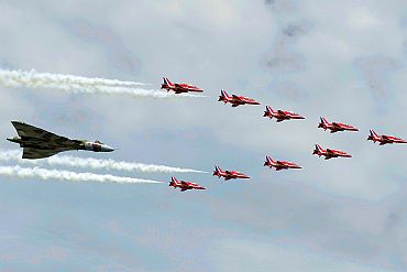 The Royal Air Force Red Arrow display team and a Vulcan aircraft fly over the 2010 Farnborough International Airshow in Farnborough, southern England