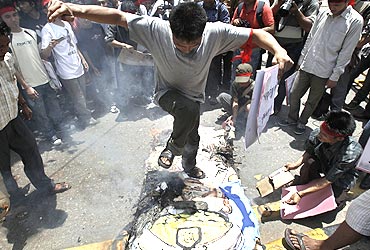 A man jumps on a burning effigy of General Than Shwe during a protest in New Delhi