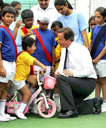 Britain's Prime Minister David Cameron signs autographs for children inside a stadium in New Delhi on Thursday