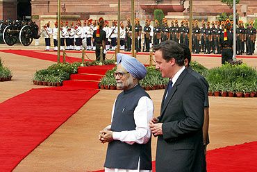 Cameron and Indian PM Manmohan Singh walk during Cameron's ceremonial reception on Thursday