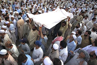 Residents carry the draped body of a suicide bomb victim to his grave in Pabbi, Peshawar