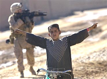 An Afghan boy gestures as US Marine from India Company, patrol in the town of Delaram in southern Afghanistan
