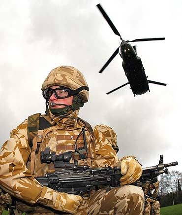 A soldier from the 1st Royal Welsh batallion waits for a chinook helicopter to land.