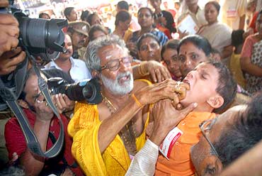 A child being given the fish prasadam