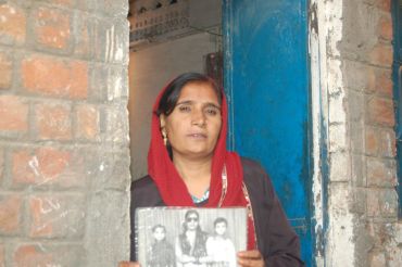 Shamshad Bi stands with a photograph of her family who died in the tragedy