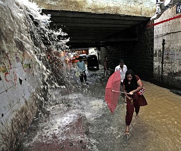 People wade through a flooded underpass road during monsoon rains in Mumbai