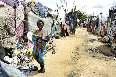 A displaced Somali girl carries dishes as she walks past her makeshift shelter in Jabuti refugee camp in south Mogadishu June 20, 2010