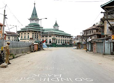 A policeman stands guard along a deserted road in Srinagar