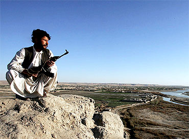 An Afghan policeman patrols mountains surrounding Helmand river valley in southern Afghanistan