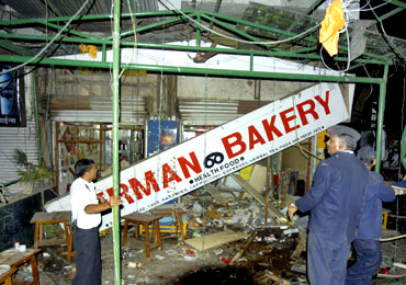 Firefighters examine the German Bakery blast site in Pune