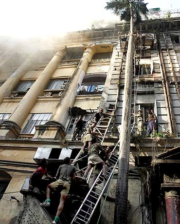 Rescuers and firemen try to evacuate people after a fire broke out in a building in Park Street, Kol