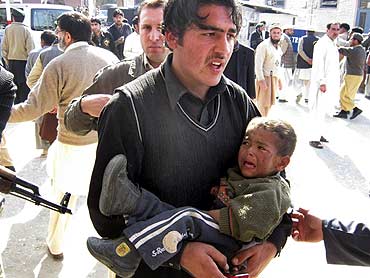 A man carries an injured boy from the site of a bombing at Timergara, Lower Dir, Pakistan