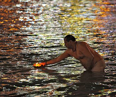 A devotee releases a lamp in the Ganga during the Kumbh Mela
