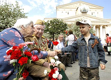 Russian World War Two veterans receive a flower from a boy in front of the Bolshoi Theatre