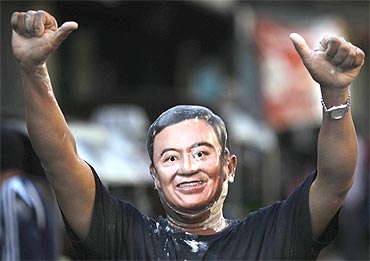 A Red Shirt supporter wears a Thaksin Shinawatra mask during protests in Bangkok
