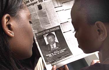 Readers look at a newspaper carrying the photograph of Felicien Kabuga
