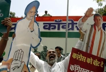A man holds cut-out images of Dr Singh and Rahul Gandhi