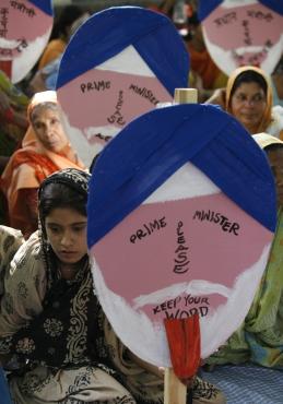 Victims of the Bhopal gas tragedy hold placards portraying Prime Minister Manmohan Singh during a protest in New Delhi