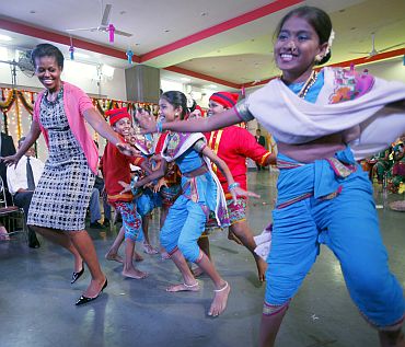 Michelle Obama dances with children during a visit to the Holy Name High School in Mumbai
