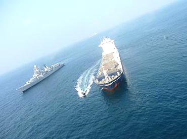 Boat with naval boarding party approaching MV Orinoco with INS Delhi in background