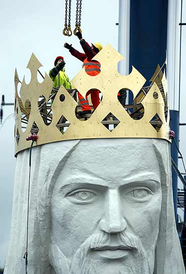 Workers attach chains to the head of the giant statue