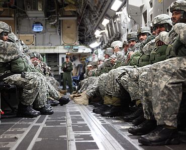 Indian and US army soldiers sit in the back of a C-17 aircraft awaiting commands from jump masters to begin their combined parachute jump November 10