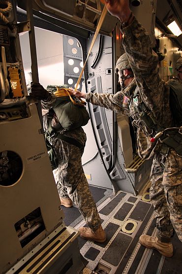 A soldier from 1st Squadron (Airborne), 40th Cavalry Regiment, 4th Brigade Combat Team (Airborne), 25th Infantry Division, assists the jump master inspection of the aircraft door in preparation for the combined parachute jump on November 10
