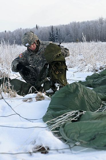 A US soldier packs his parachute after landing at Malamute drop-zone
