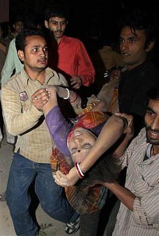 Local residents and rescue workers remove the body of a woman from the debris