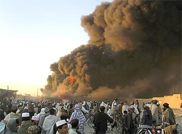 Tribesmen gather near burning fuel tankers after they were attacked in Chaman in Pakistan's Balochistan province