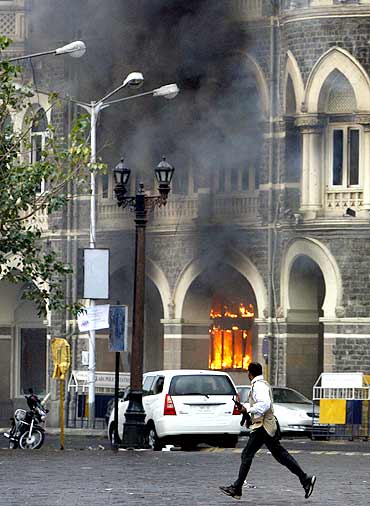 A member of the anti-terrorist squad runs in front of the burning Taj Mahal hotel during a gun battle in Mumbai