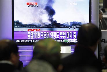 Koreans watch a TV showing smoke rising from Yeonpyeong Island after it was hit by dozens of artillery shells fired by North Korea at  Yeonpyeong Island