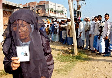 A Muslim woman holds her voter's identity card outside a polling booth in Jahanabad, Bihar