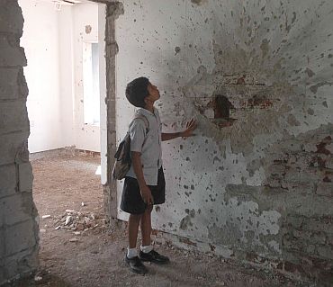 A schoolkid looks at the bullet holes at Nariman House