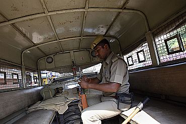 A policeman checks his gun as he sits inside a police vehicle in Lucknow on Thursday