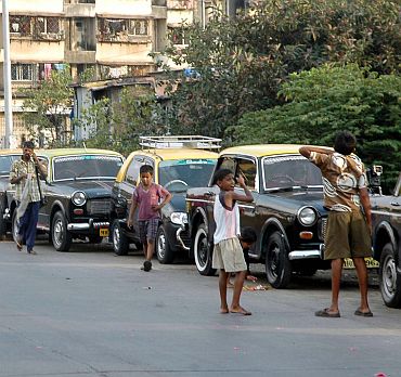 Children play on a deserted street beside a line of stranded taxis in Mumbai on Thursday