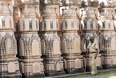 A paramilitary trooper walks past pillars to be used in constructing a temple in Ayodhya