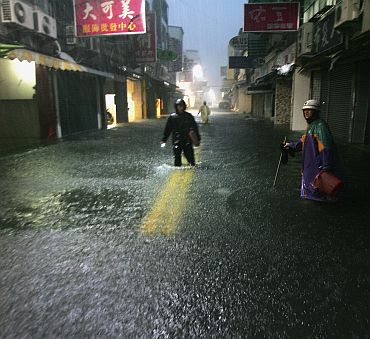 People walk along a flooded street as Typhoon Fanapi hits Kaohsiung City, southern Taiwan on September 19, 2010. Typhoon Fanapi, Taiwan's most severe storm so far in 2010, brought 162 kph (101 mph) maximum wind gusts that caused injuries by toppling scooters, breaking glass and blowing down signs