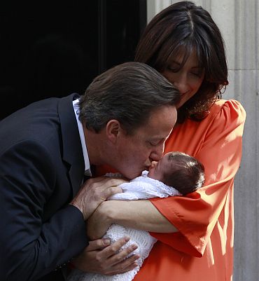Britain's Prime Minister David Cameron kisses his new baby daughter, Florence Rose Endellion, as he stands with his wife Samantha outside Number 10 Downing Street in London on September 3