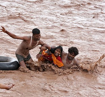Rescuers help a woman to move a safer place from flooded Ghaghar river after heavy rains in Punchkula in Haryana on September 8
