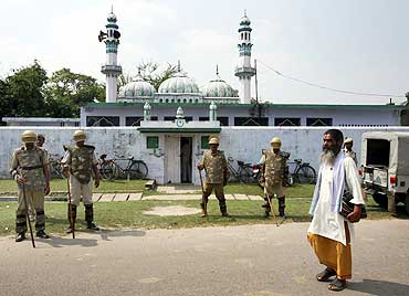 A priest walks past a mosque in Ayodhya