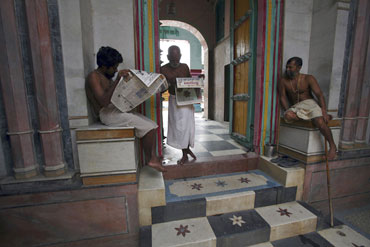 Priests read newspapers inside a temple in Ayodhya