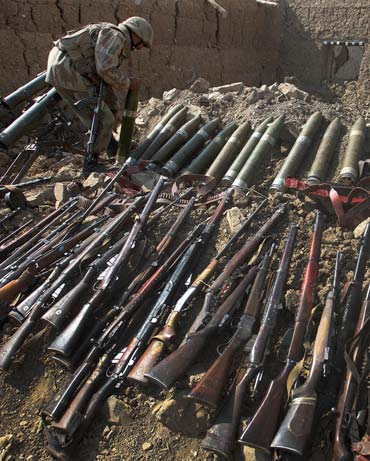 A Pakistan soldier with weapons and ammunition recovered during operations against the Taliban