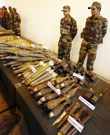Indian army soldiers stand behind seized ammunition from a militant hideout in a camp near Srinagar