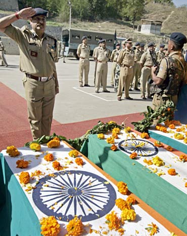 A CRPF officer salutes in front of coffins containing the bodies of slain colleagues