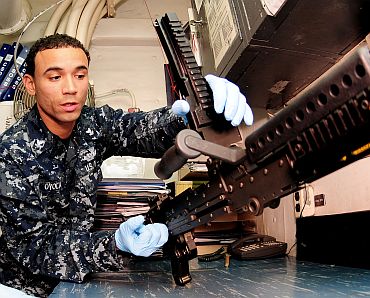 Gunner's Mate 2nd Class Edward P Oyola cleans an M-240B machine gun in the armory of the USS Essex