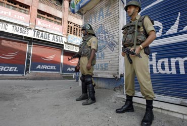 Policemen guard a market in Srinagar during a curfew